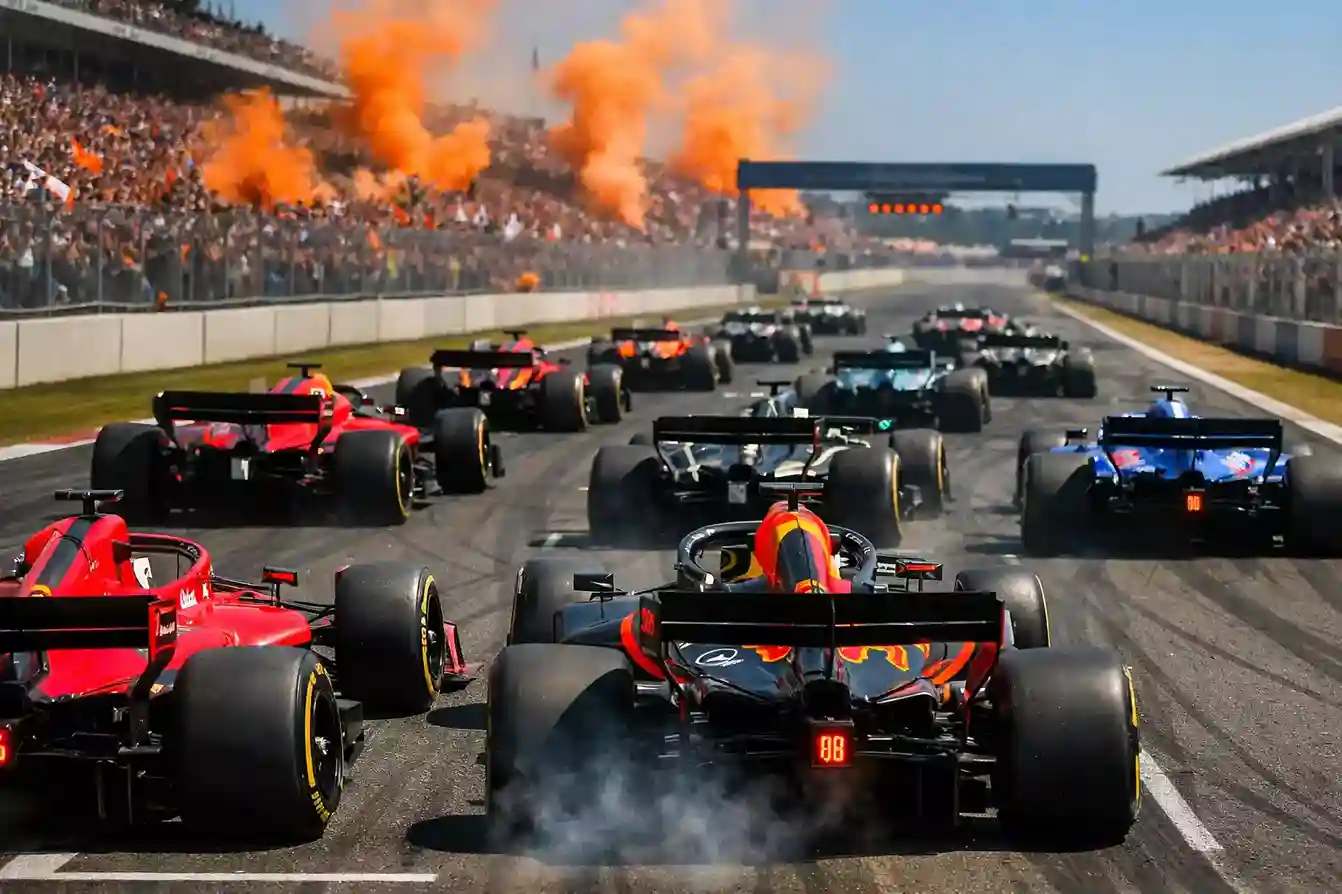 Formule 1 racewagens op de startgrid van Circuit Zandvoort met oranje rookwolken van Nederlandse fans